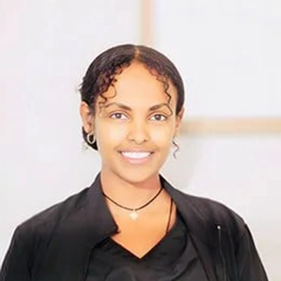 Staff Member Erusalem Smiling In Front Of Blurred Office Background