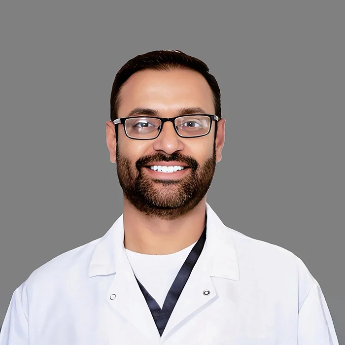 Dentist Sushen Sharma Smiling In White Lab Coat